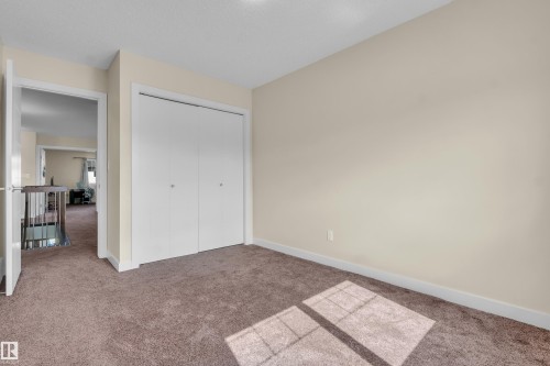 Neutral tone walls with white trim, brown carpeting, and a built-in closet with white bifold doors - 3071 Carpenter Landing Sw, Edmonton, AB 