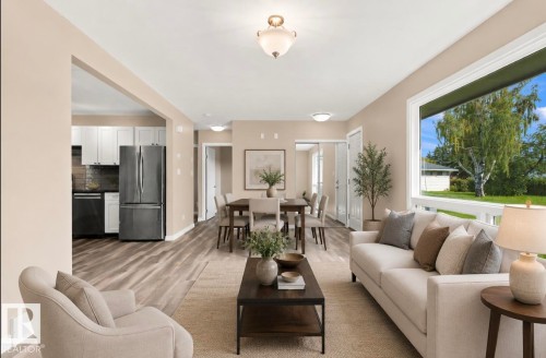 Spacious living area featuring wood-finish flooring, neutral wall tones, and a large picture window - 15812 110A Avenue Nw, Edmonton, AB 