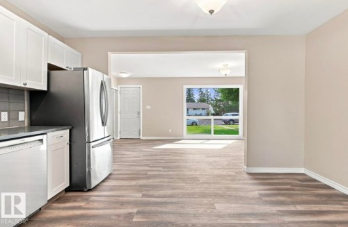 Kitchen featuring white cabinetry, stainless steel appliances, and wood-finish flooring - 15812 110A Avenue Nw, Edmonton, AB 