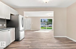 Kitchen featuring white cabinetry, stainless steel appliances, and wood-finish flooring - 