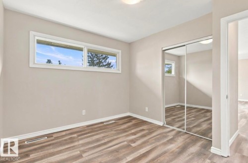 Wood-finish flooring, two large windows, mirrored closet doors, and recessed ceiling lighting - 15812 110A Avenue Nw, Edmonton, AB 