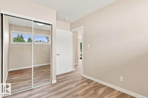 Sliding mirrored closet doors, wood-finish flooring, white trim, and a white interior door - 15812 110A Avenue Nw, Edmonton, AB 