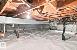 Crawl space with exposed wood joists, structural beam, plumbing, and a white vapor barrier covering the ground - 