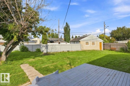 Expansive grassy yard with a detached garage structure, wood decking, and privacy fencing - 15812 110A Avenue Nw, Edmonton, AB 