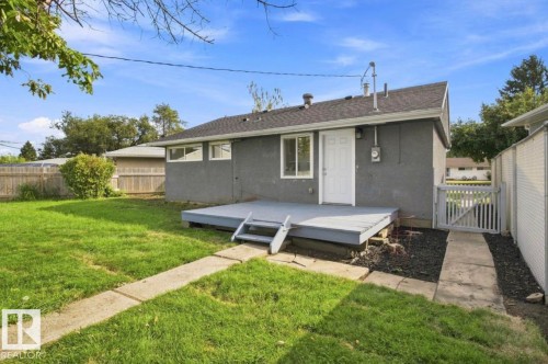 Expansive backyard featuring a concrete patio, wooden deck with stairs, white exterior door, and fenced perimeter - 15812 110A Avenue Nw, Edmonton, AB 