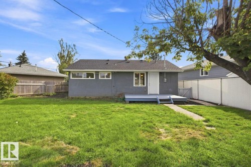 Expansive rear yard featuring a grass lawn, a rear deck, and a concrete pathway - 15812 110A Avenue Nw, Edmonton, AB 