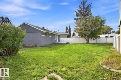 Expansive rear yard featuring green space, mature trees, and a white privacy fence - 