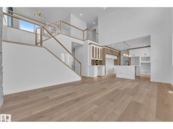Open-concept living space with wood-finish flooring, a two-story ceiling, and a modern kitchen - 