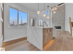 Central island with integrated sink and matte black faucet, wood-finish cabinetry, and waterfall countertop - 