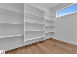 Built-in white shelving, wood-finish flooring, and a large horizontal window - 