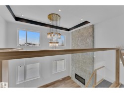 Upper-level featuring a multi-tiered chandelier, recessed lighting, and a stone-clad fireplace with an integrated linear insert - 