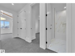 White interior doors with black hardware, recessed ceiling lighting, gray carpet flooring, and white tile flooring in the bathroom featuring a built-in tub - 
