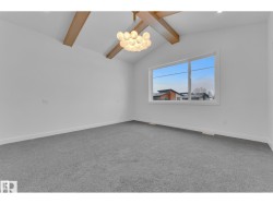Vaulted ceiling with exposed wood beams, modern bubble chandelier, large window, and light gray carpeting - 