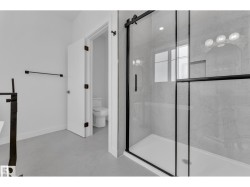 Glass-enclosed shower with black-framed sliding door and marble-patterned tile surround - 