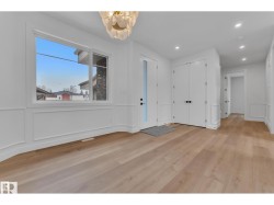 Wide plank wood-finish flooring, white paneled walls, a single-pane window, and a decorative overhead light fixture - 