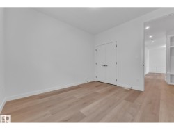 Light wood-finish flooring, white walls, and built-in closet with double doors - 
