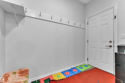 Entryway featuring a white paneled door with brushed nickel hardware, light gray walls, white baseboards, and a built-in white shelf with coat hooks - 2606 Donaghey Crescent Sw, Edmonton, AB - Indoor Photo Showing Other Room