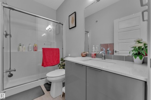 Full bathroom featuring a glass-enclosed shower-tub combination, a white toilet, and a vanity with a white countertop - 2606 Donaghey Crescent Sw, Edmonton, AB - Indoor Photo Showing Bathroom
