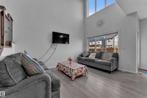 Vaulted ceilings with upper-level windows, wood-finish flooring, and a large ground-level window - 2606 Donaghey Crescent Sw, Edmonton, AB - Indoor Photo Showing Living Room