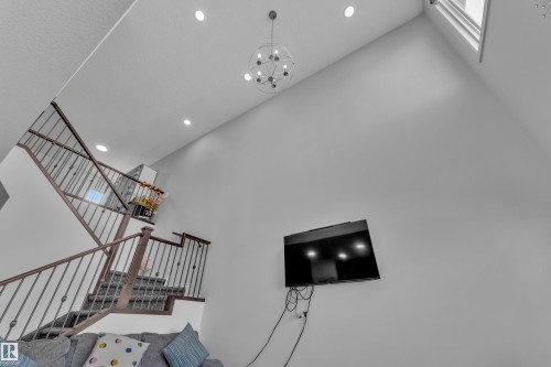Two-story living area featuring a vaulted ceiling with recessed lighting and a contemporary chandelier - 2606 Donaghey Crescent Sw, Edmonton, AB - Indoor Photo Showing Other Room