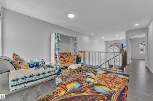 Open loft area featuring recessed lighting, dark wood-finish flooring, and a railing with dark wood posts and metal spindles overlooking the floor below - 2606 Donaghey Crescent Sw, Edmonton, AB - Indoor Photo Showing Other Room