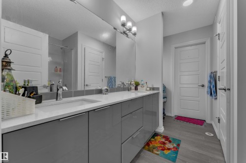 Double vanity with light gray cabinetry and white countertops, featuring chrome fixtures and an oversized mirror - 2606 Donaghey Crescent Sw, Edmonton, AB - Indoor Photo Showing Bathroom