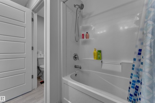White bathtub and shower combination unit featuring an integrated soap dish and shelf - 2606 Donaghey Crescent Sw, Edmonton, AB - Indoor Photo Showing Bathroom