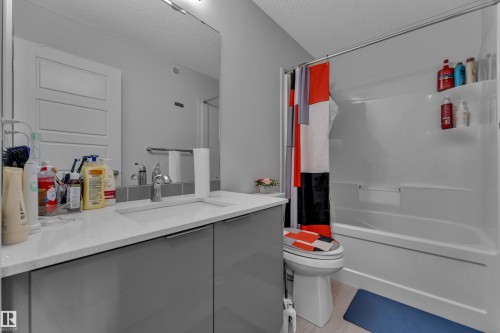Contemporary bathroom featuring a white integrated sink, polished chrome faucet, grey vanity cabinetry, and a large wall-mounted mirror - 2606 Donaghey Crescent Sw, Edmonton, AB - Indoor Photo Showing Bathroom