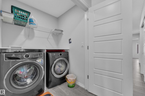 Dedicated laundry area featuring a front-loading washer and dryer, a white countertop, and an overhead wire shelving system - 2606 Donaghey Crescent Sw, Edmonton, AB - Indoor Photo Showing Laundry Room