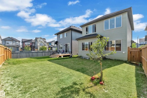 Expansive fenced backyard featuring a grassy lawn, a private deck, and a mature tree - 2606 Donaghey Crescent Sw, Edmonton, AB - Outdoor