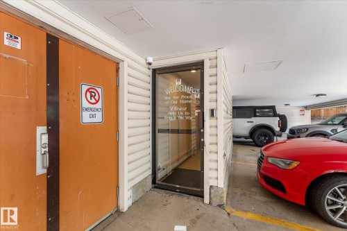 Enclosed parking area with a concrete floor, security camera, and overhead lighting - #205 8125 110 St Nw, Edmonton, AB 