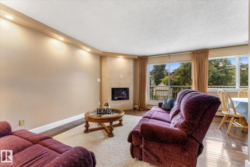 Recessed ceiling lighting, a built-in fireplace, expansive windows, hard-surface flooring, and a balcony - #205 8125 110 St Nw, Edmonton, AB 