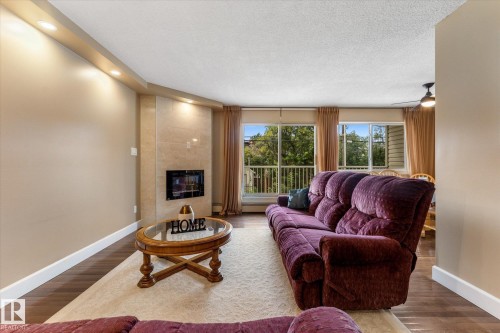 Wood-finish flooring, recessed ceiling lighting, light-toned wall finishes, and a built-in fireplace - #205 8125 110 St Nw, Edmonton, AB 