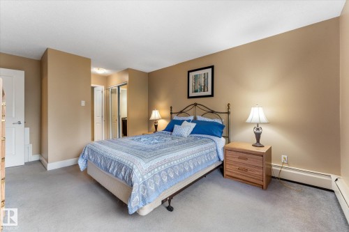 Carpeted flooring, neutral wall paint, white trim, solid core interior doors, and a closet with sliding mirrored doors - #205 8125 110 St Nw, Edmonton, AB 