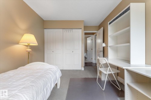 Built-in shelving and desk unit, bi-fold closet doors, and neutral wall tones - #205 8125 110 St Nw, Edmonton, AB 