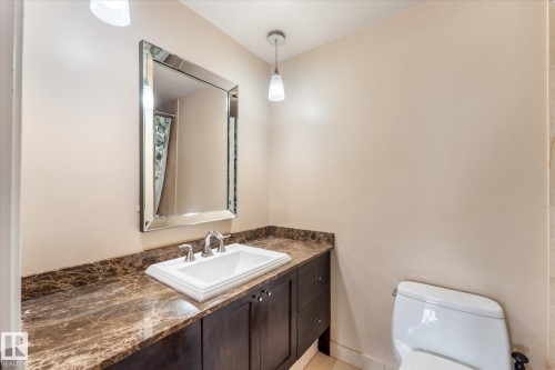 Dark wood-finish vanity with an undermount sink, patterned countertop, and framed mirror - #205 8125 110 St Nw, Edmonton, AB 