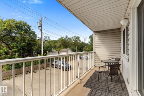 Balcony featuring vinyl siding, white railing, and an overhead light fixture - #205 8125 110 St Nw, Edmonton, AB 
