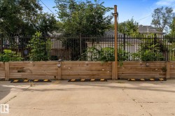 Paved parking area featuring designated spaces, timber retaining wall, and wrought iron fencing - 