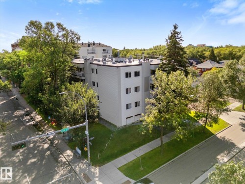 Modern low-rise building with multiple levels, featuring a flat roof and surrounding mature trees - #205 8125 110 St Nw, Edmonton, AB 