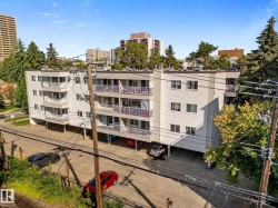 Multi-story building with white siding, multiple balconies, and an integrated carport parking area - 