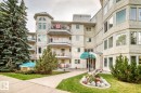 Building entrance featuring a turquoise awning with property identification, glass doors, and textured exterior wall - #208 2520 52 St Nw, Edmonton, AB 
