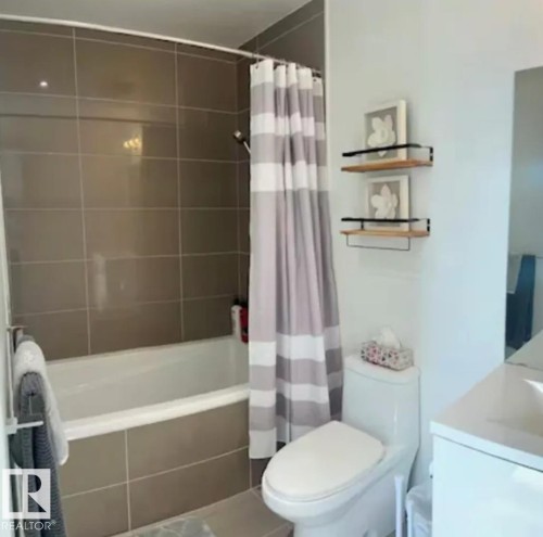 Bathtub and shower combination, large format tile shower surround, toilet, and wall-mounted shelving - #1006 1010 6 St Sw, Calgary, AB 