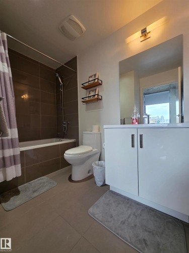 White vanity with dual cabinet doors, integrated sink, and large wall-mounted mirror - #1006 1010 6 St Sw, Calgary, AB 