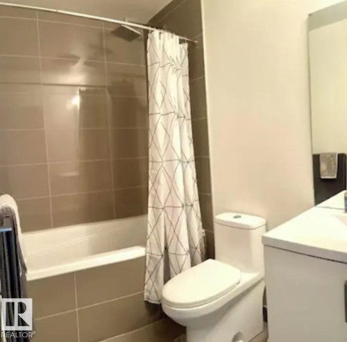Alcove bathtub with large format wall tiling, rain shower head, and an adjacent toilet - #1006 1010 6 St Sw, Calgary, AB 