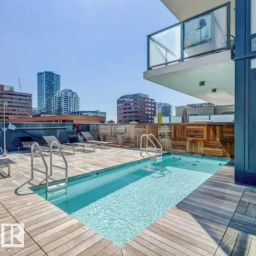 Rooftop deck featuring a rectangular swimming pool, wood-finish decking, and contemporary glass railings - #1006 1010 6 St Sw, Calgary, AB 
