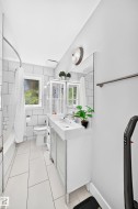 White subway tile shower surround, rectangular vanity mirror, single basin vanity with integrated sink, white tile flooring, and a window with privacy glass - 