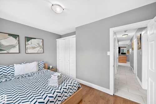 Hardwood-finish flooring, white bi-fold closet doors, and a ceiling-mounted light fixture - 10139 74 Street Nw, Edmonton, AB 