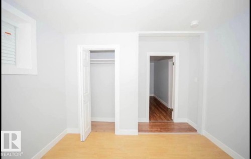 Light wood-finish flooring, white walls, and a built-in closet with a white door - 10139 74 Street Nw, Edmonton, AB 