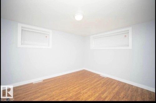 Recessed windows with blinds, wood-finish flooring, and white wall paint - 10139 74 Street Nw, Edmonton, AB 