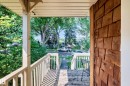Covered porch featuring wood-finish siding, white railings, and a wood-finish floor - 10139 74 Street Nw, Edmonton, AB 